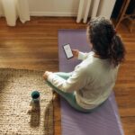스트레스, 일상 속 작은 변화로 관리한다…최근 주목받는 ‘마이크로 습관’ 실천법 Woman meditating on yoga mat with phone and drink.