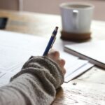 “끊이지 않는 피로감, ‘만성피로’ 극복하는 생활 속 작은 변화” person writing on brown wooden table near white ceramic mug