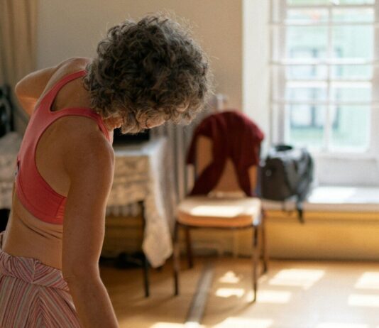 ‘마이크로 운동’이 부상한다… 바쁜 일상 속 건강 챙기는 새로운 습관 Woman with grey hair stretching in a sunlit room